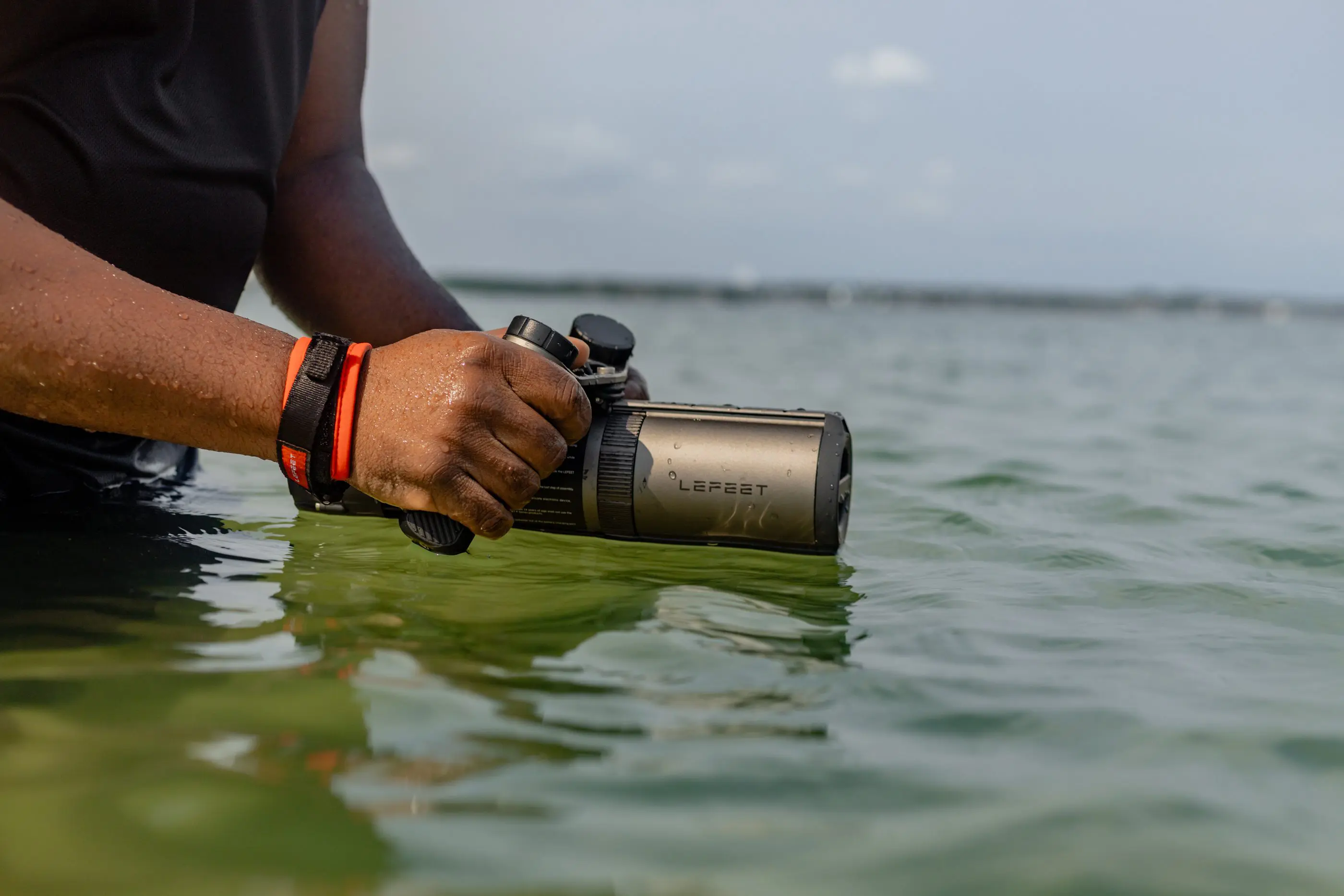Hands holding monocular partially submerged in water