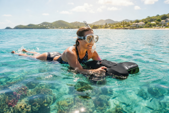 Swimmer gliding across clear turquoise water with a sea scooter